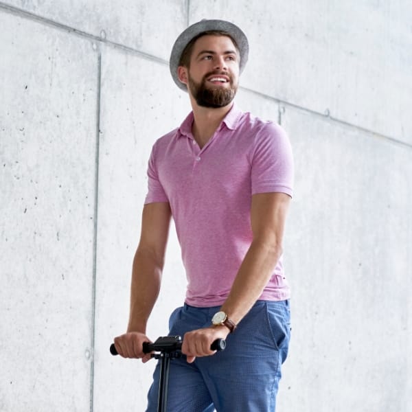Jeune homme souriant au volant de sa trotinette